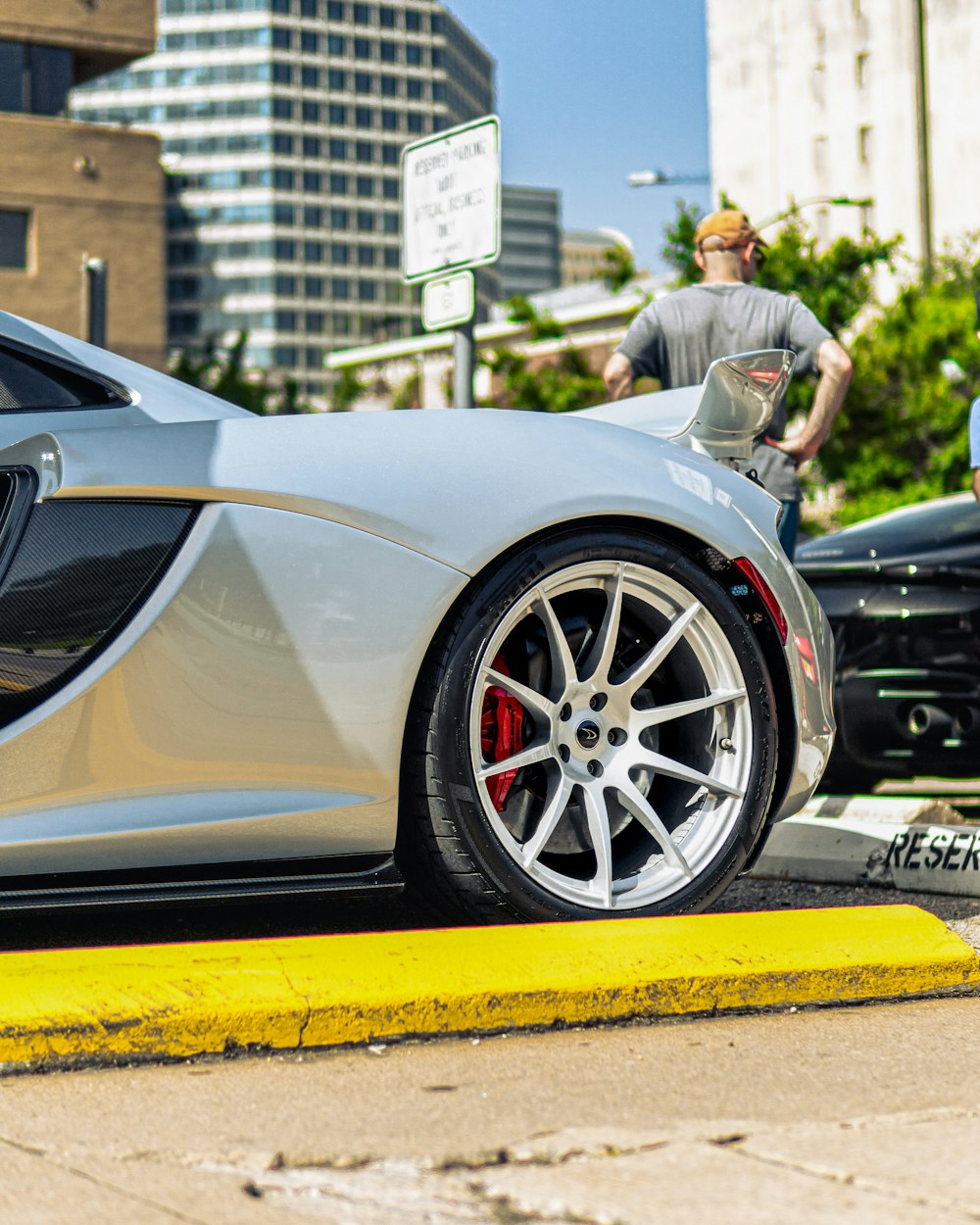 a man standing next to a silver sports car