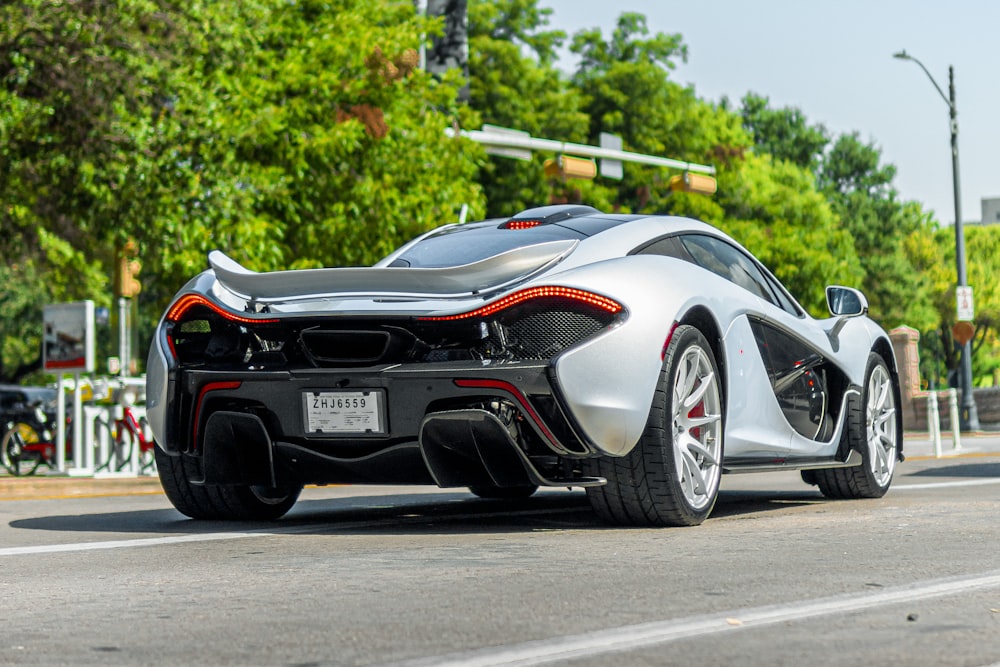 a silver sports car driving down a street