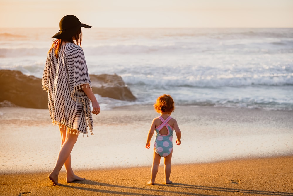 a woman and a child walking on the beach