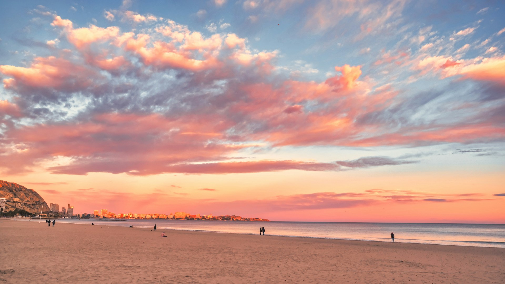 a beach with people walking on it at sunset