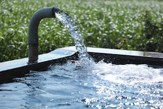 a water spouting from a pipe into a pool of water
