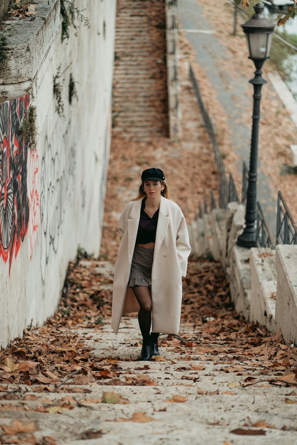 a woman in a white coat is walking down the street