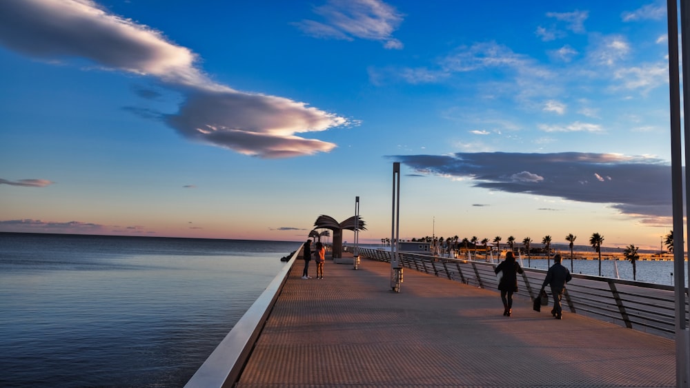people walking along a pier near the ocean