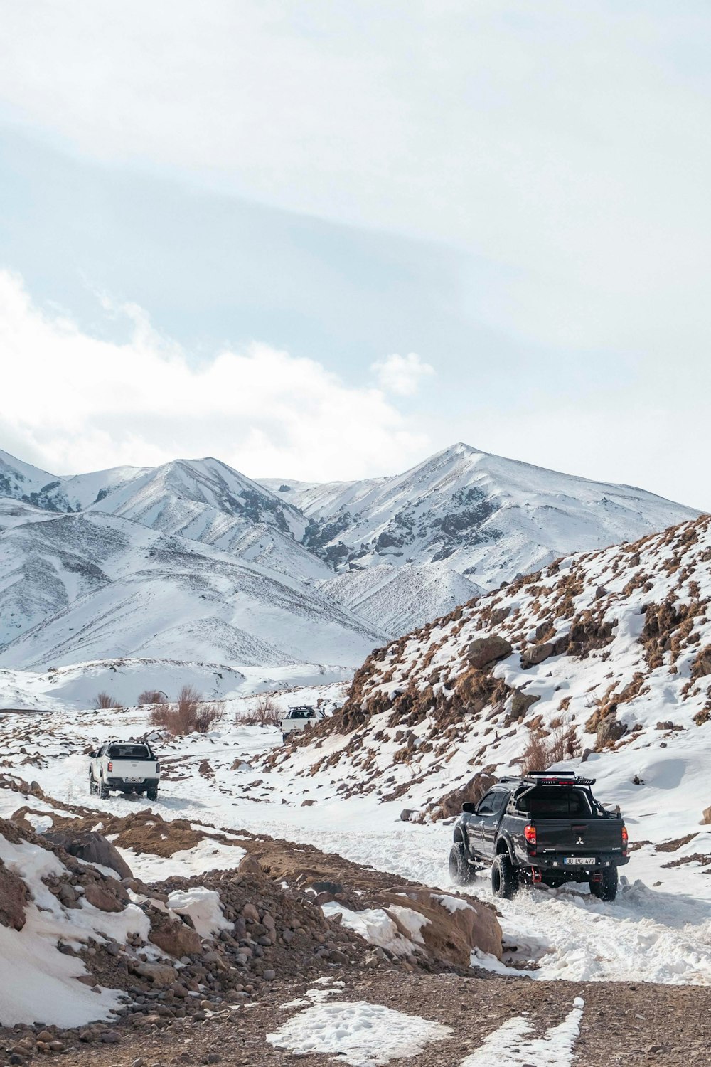 a couple of trucks driving down a snow covered road