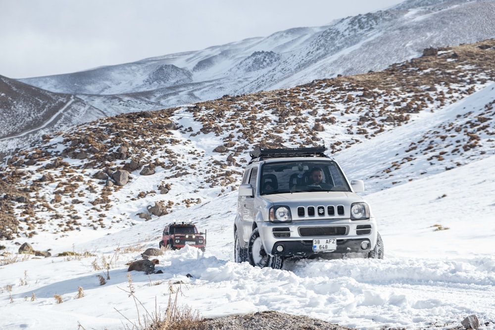 a jeep driving through the snow in the mountains