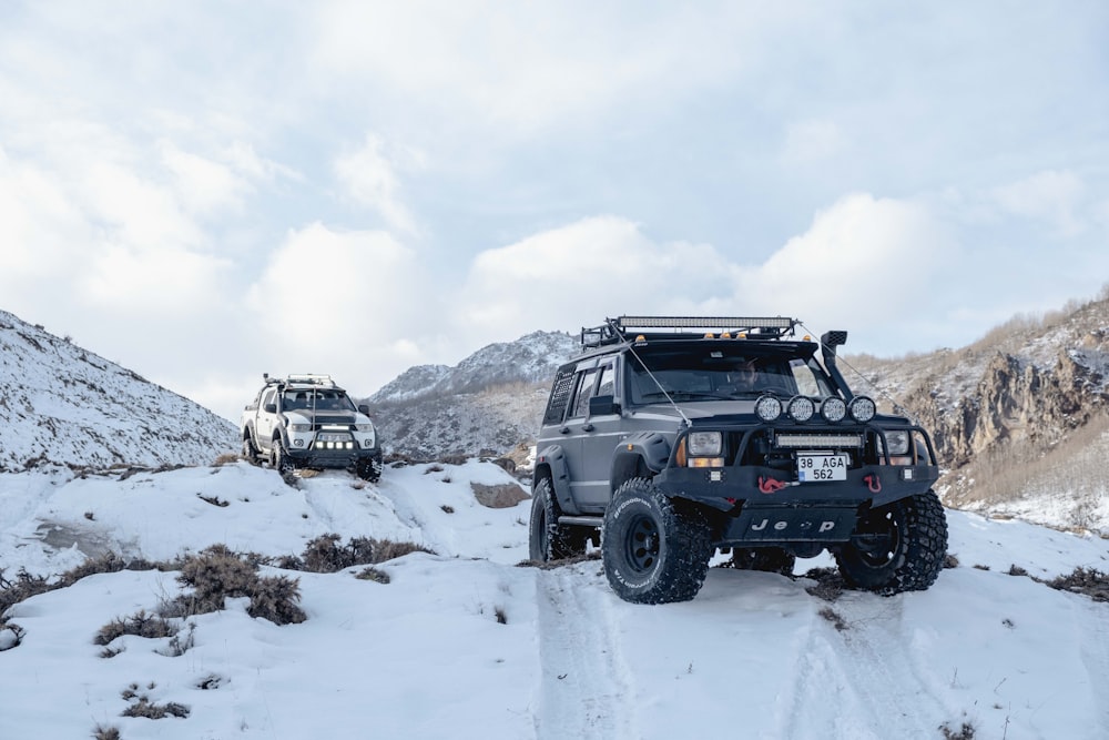 a couple of vehicles driving down a snow covered road