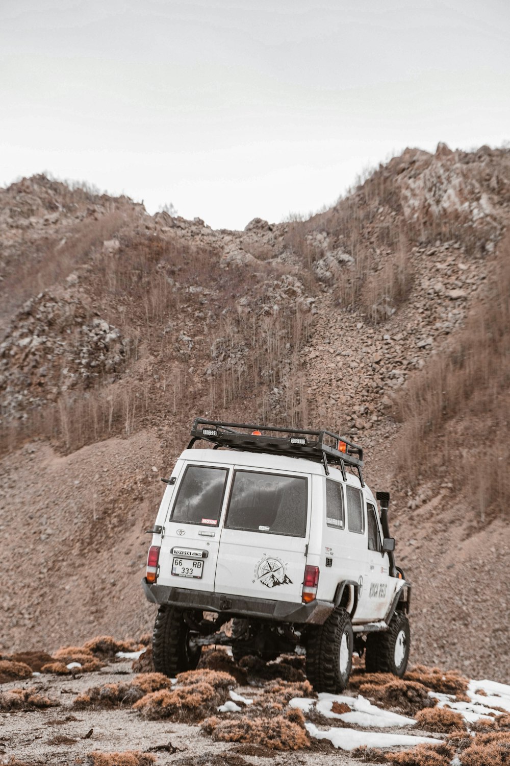 a white suv parked on top of a rocky hill