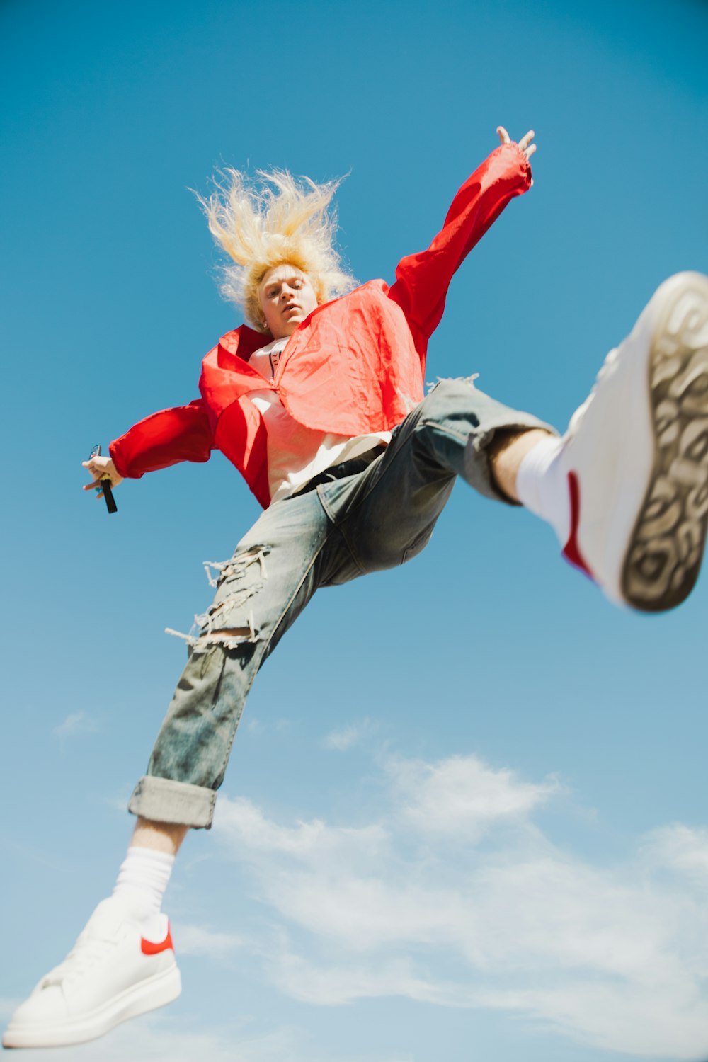 a woman in a red jacket is doing a trick on a skateboard