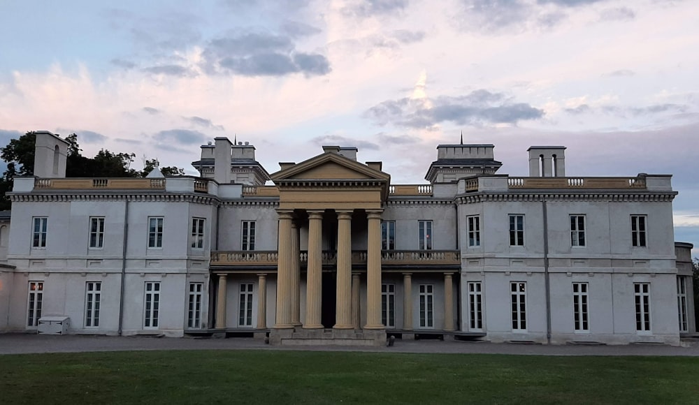 a large white building sitting on top of a lush green field