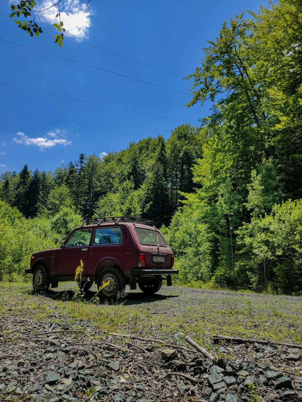 a red car parked on the side of a dirt road