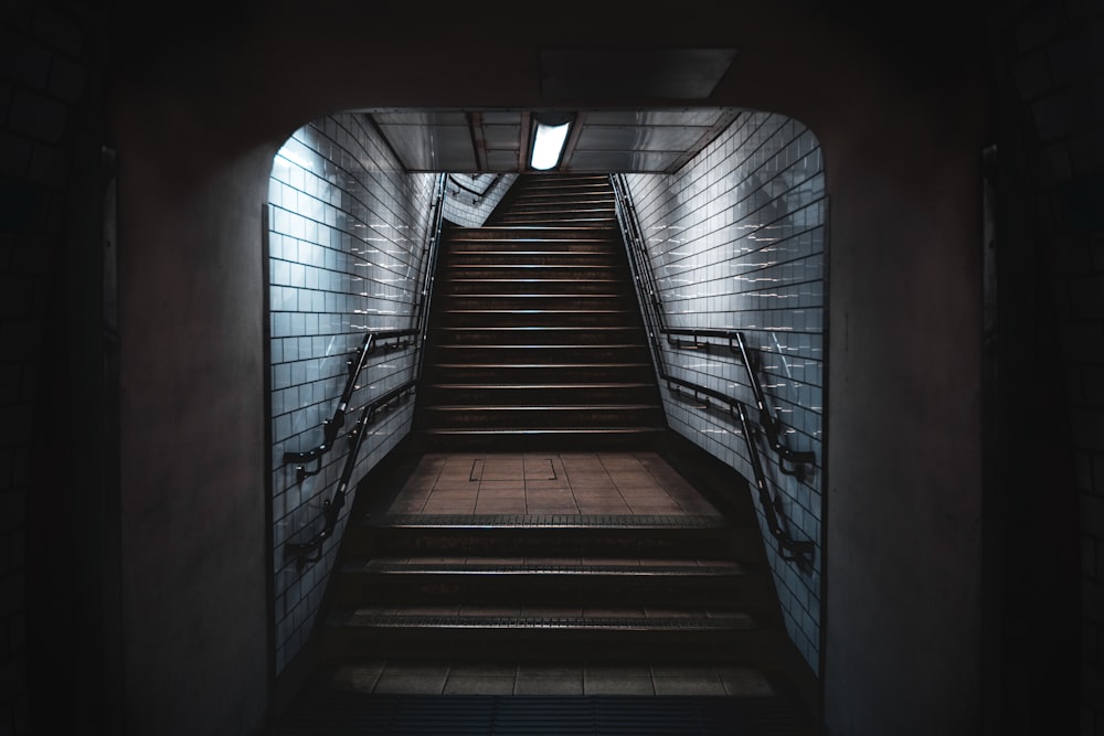 a set of stairs leading up to a light at the end of a tunnel