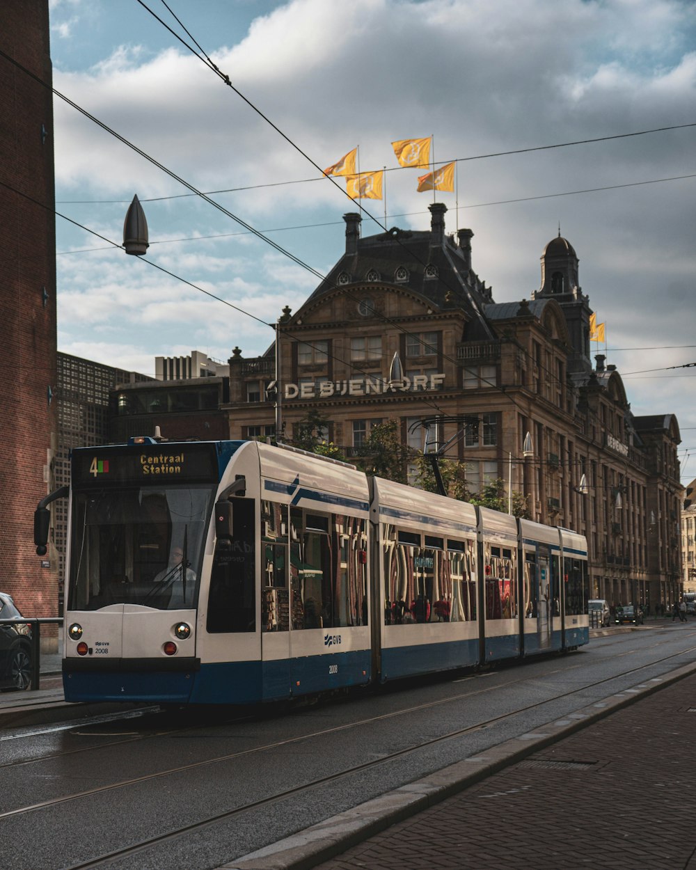 a blue and white train traveling past a tall building