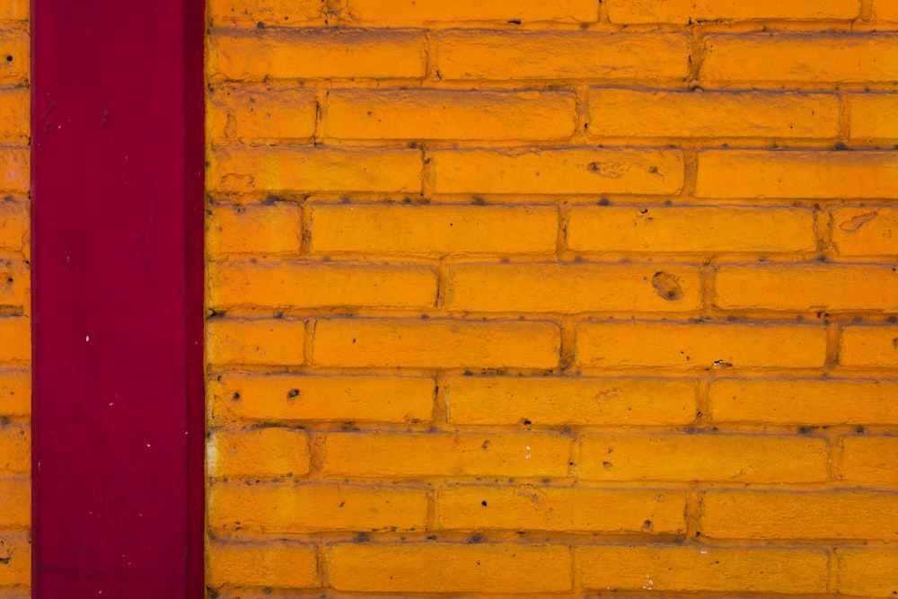 un muro di mattoni gialli con una striscia rossa
