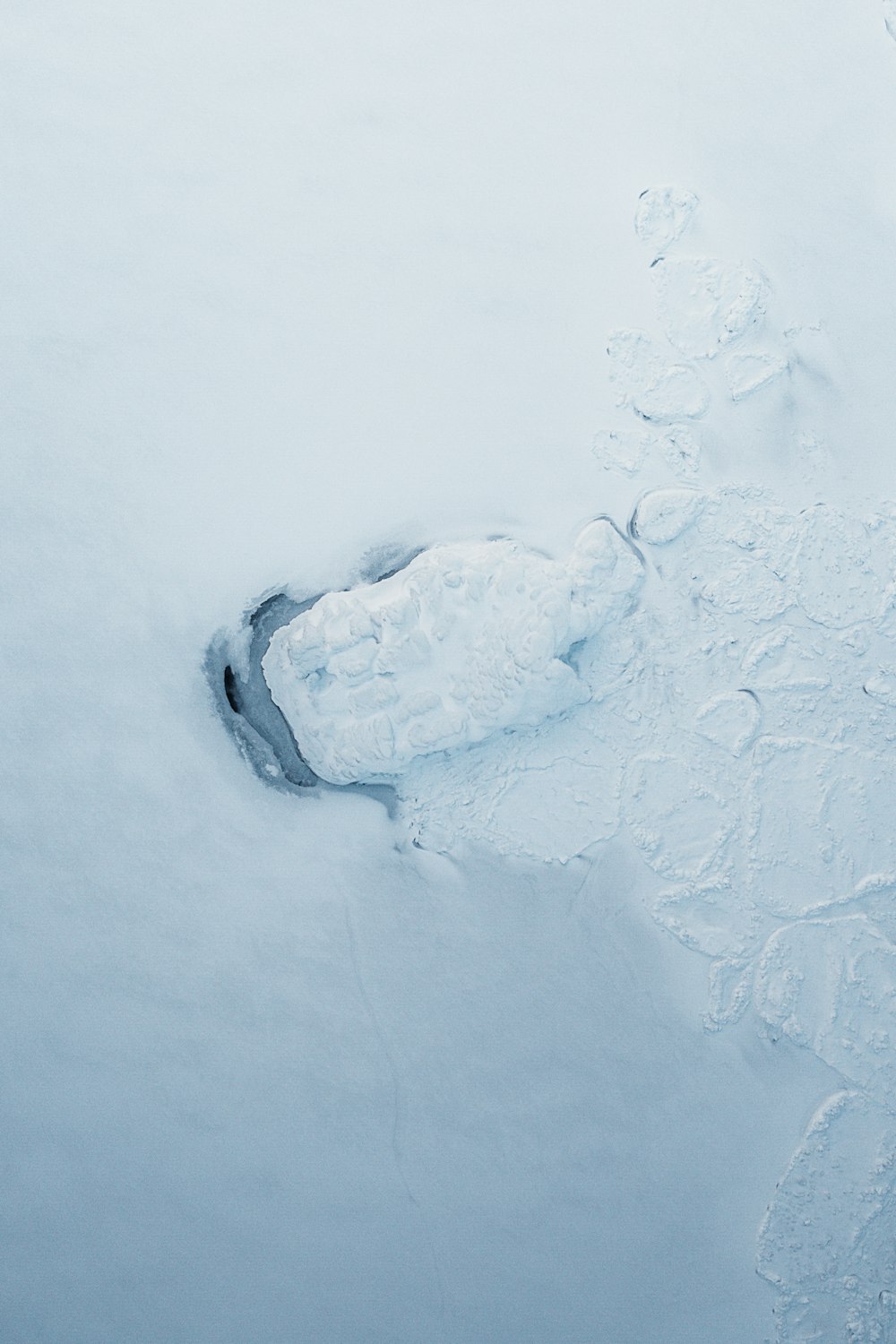 a snow covered ground with a small hole in the middle