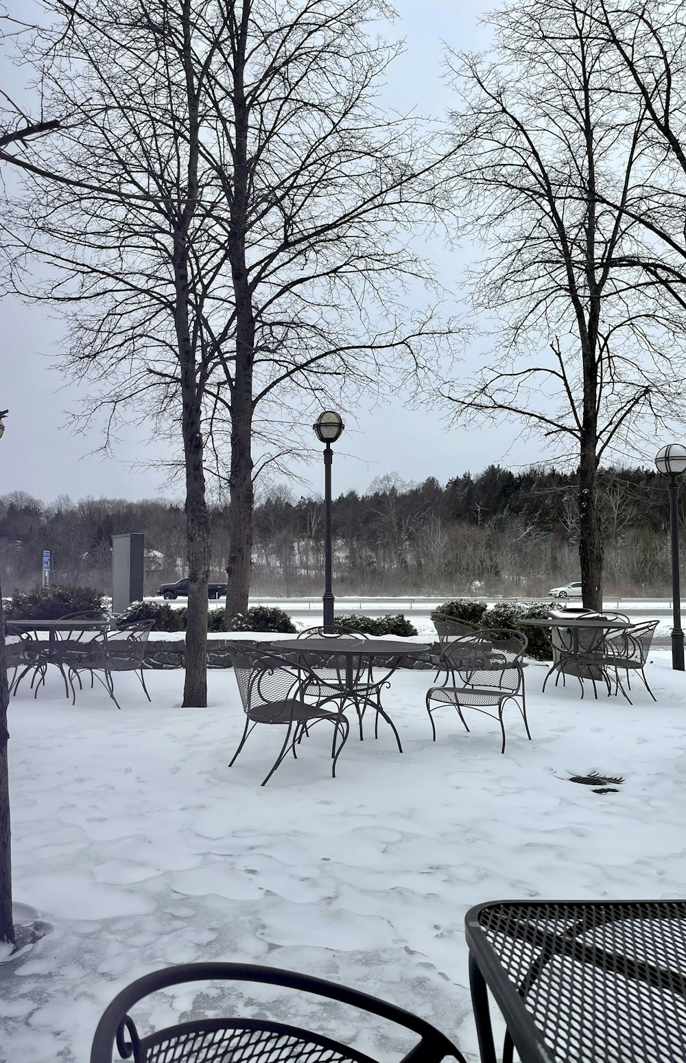 a park with tables and chairs covered in snow