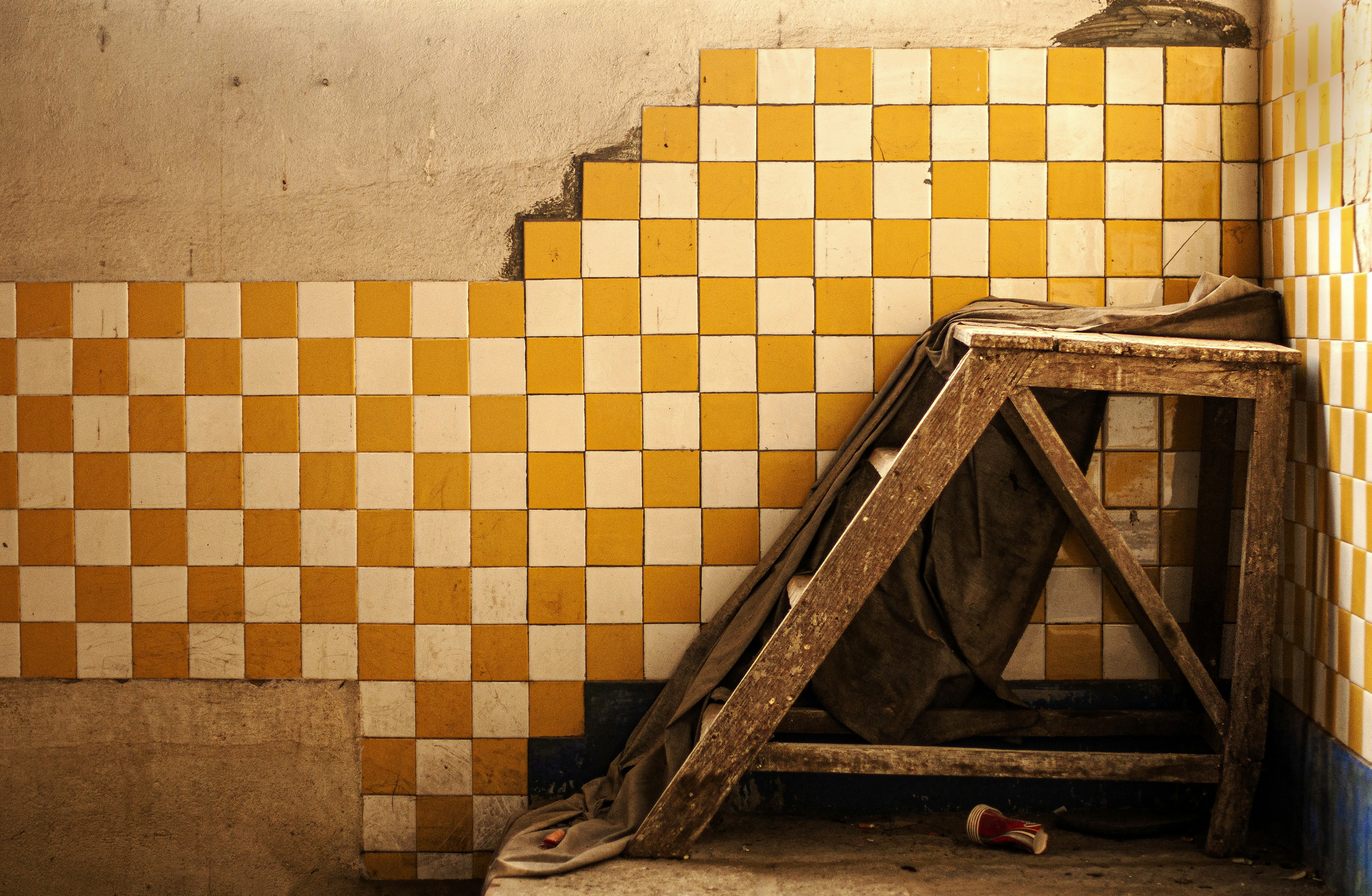 a yellow and white tiled wall next to a wooden ladder