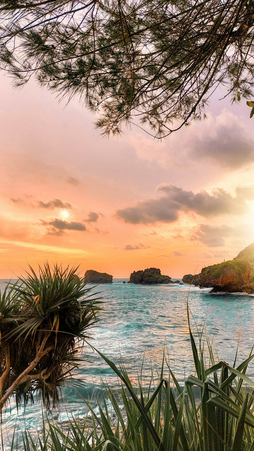 the sun is setting over the ocean and a beach