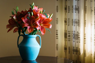 Close-up of orange lilies beside traditional crafts on a sunlit wooden table