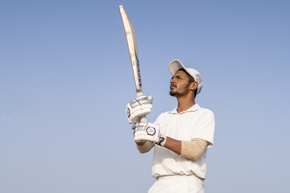 a man in a white uniform holding a baseball bat