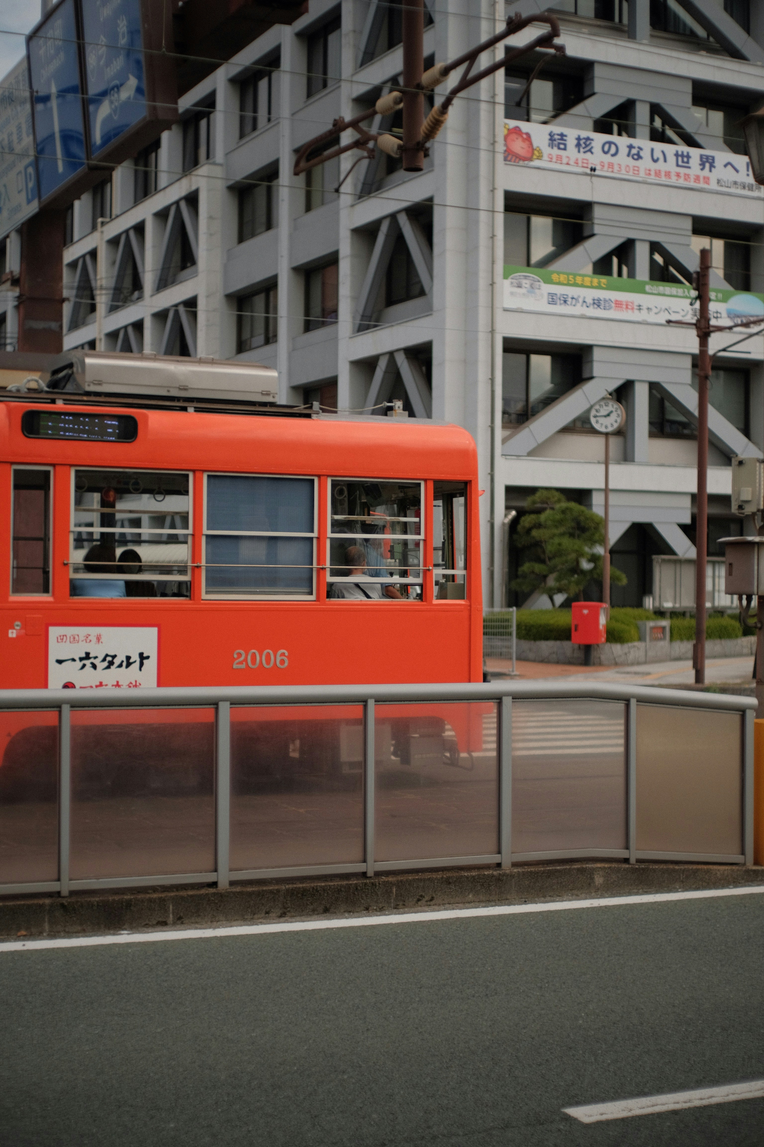 a red train traveling down a street next to tall buildings