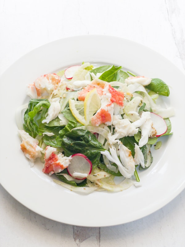 A white plate topped with a salad covered in shrimp