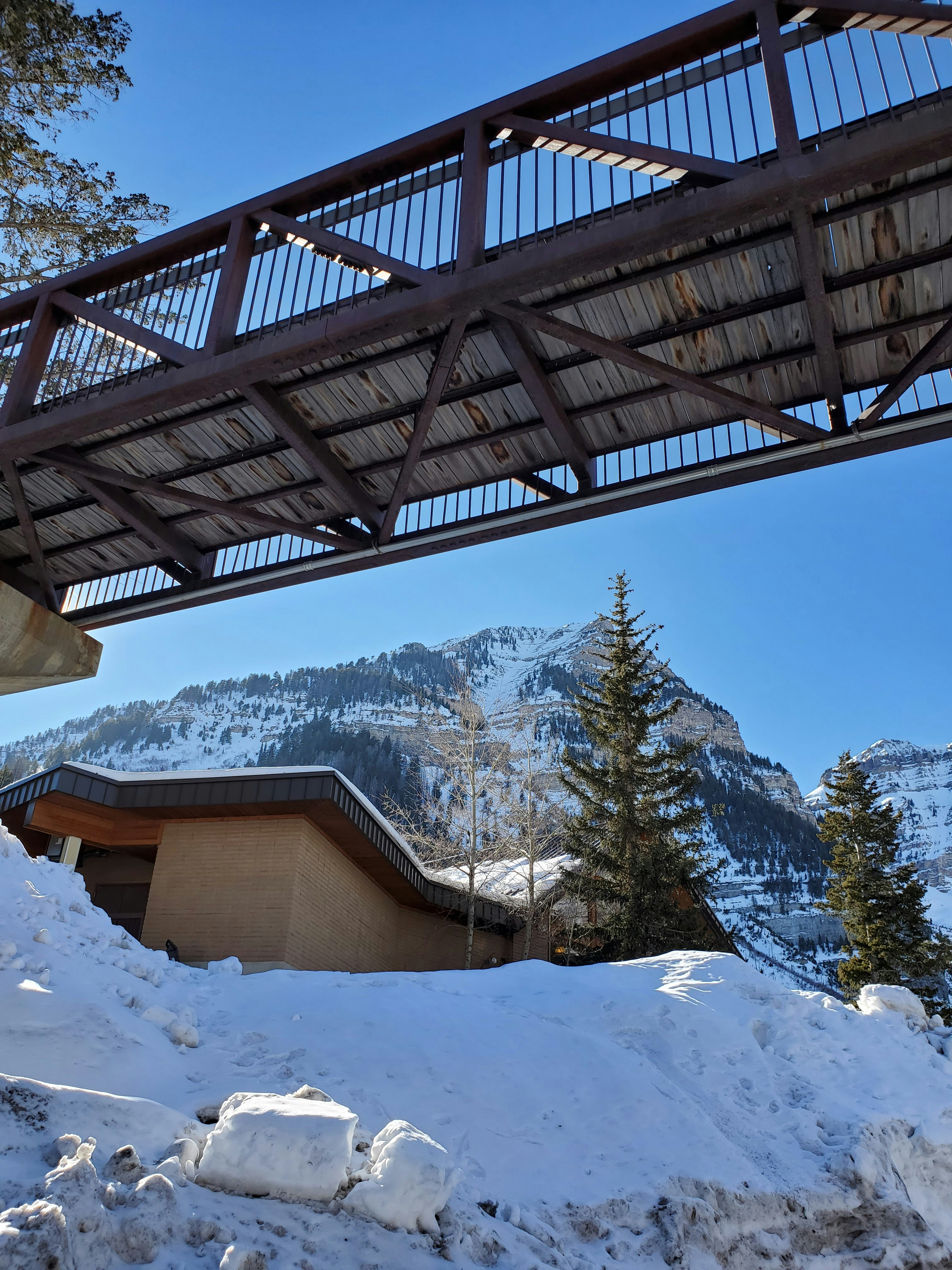 a bridge over a snow covered mountain with a building in the background