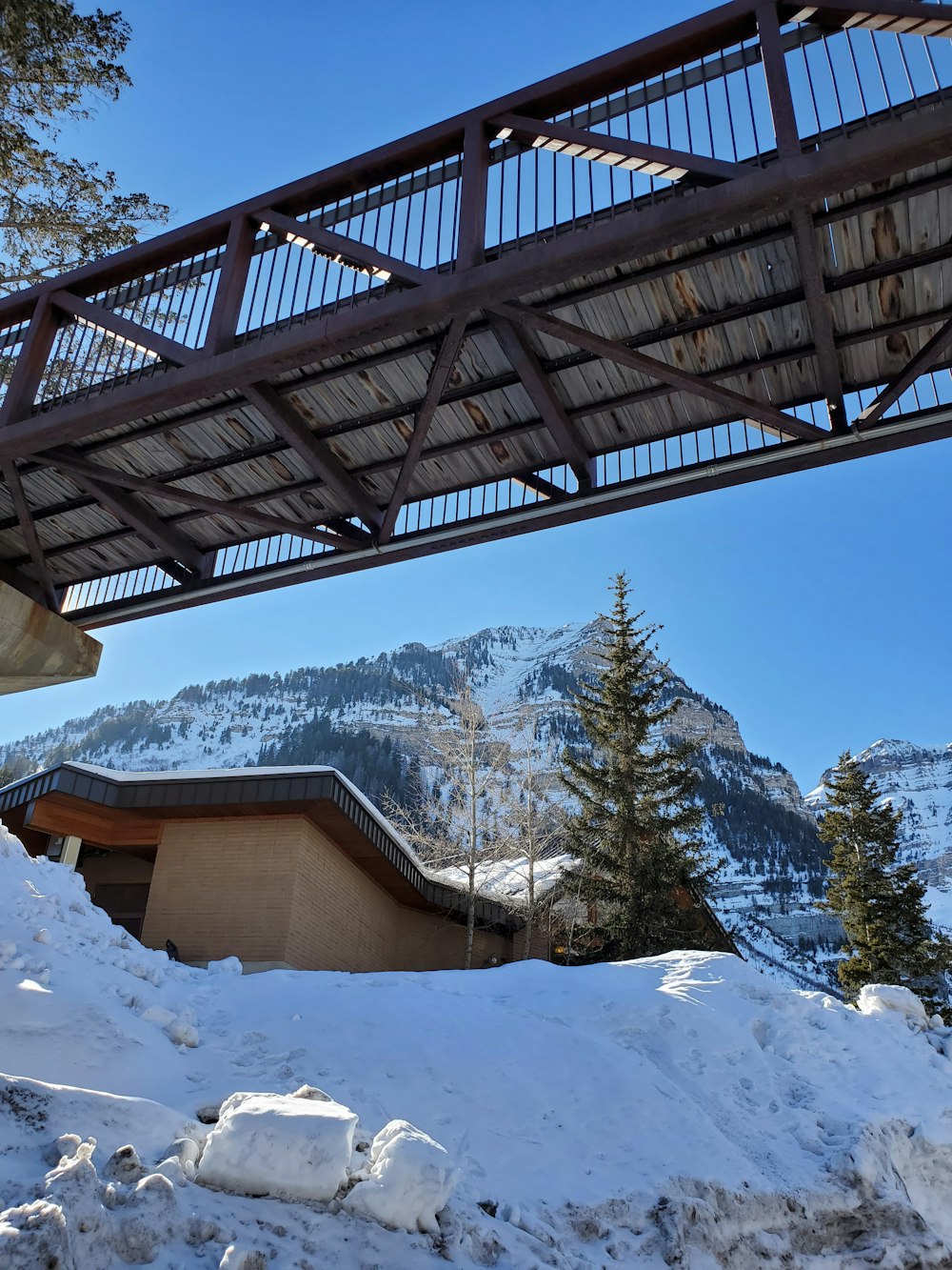 a bridge over a snow covered mountain with a building in the background