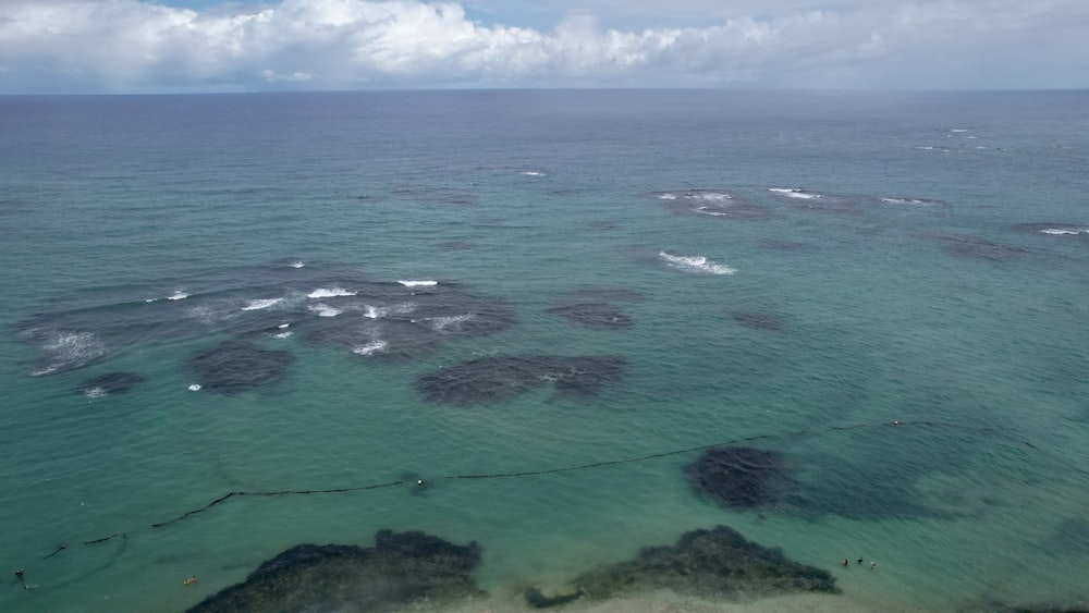 an aerial view of the ocean with rocks in the water