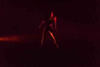 Powerful silhouette of a fighter standing in the cage under dramatic red lighting, embodying strength and determination.
