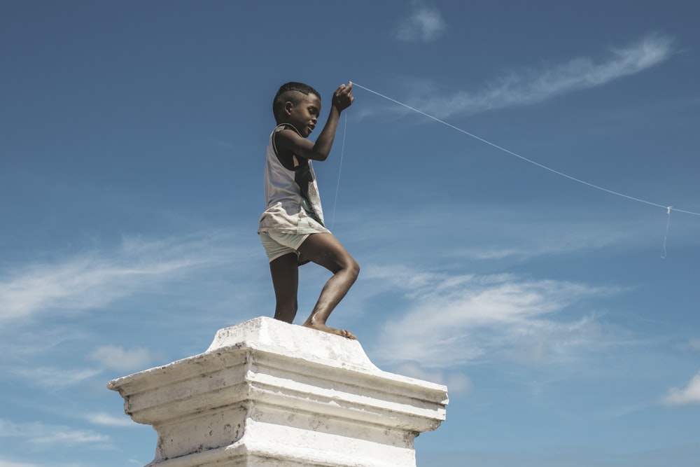 a young boy flying a kite on top of a statue