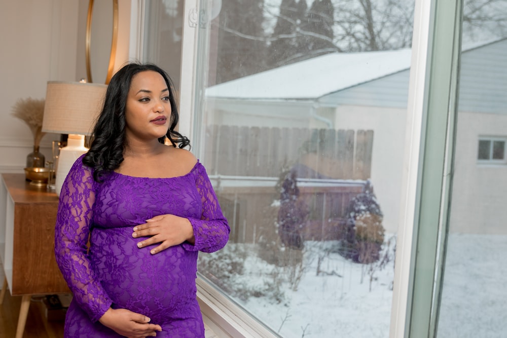 a pregnant woman standing in front of a window