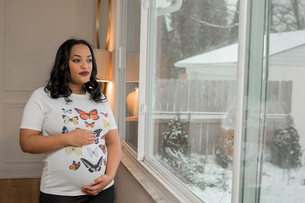 a pregnant woman standing in front of a window