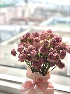 a vase filled with pink flowers on top of a window sill