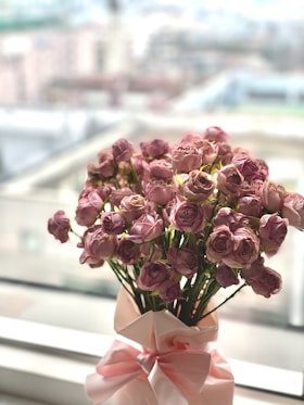 a vase filled with pink flowers on top of a window sill
