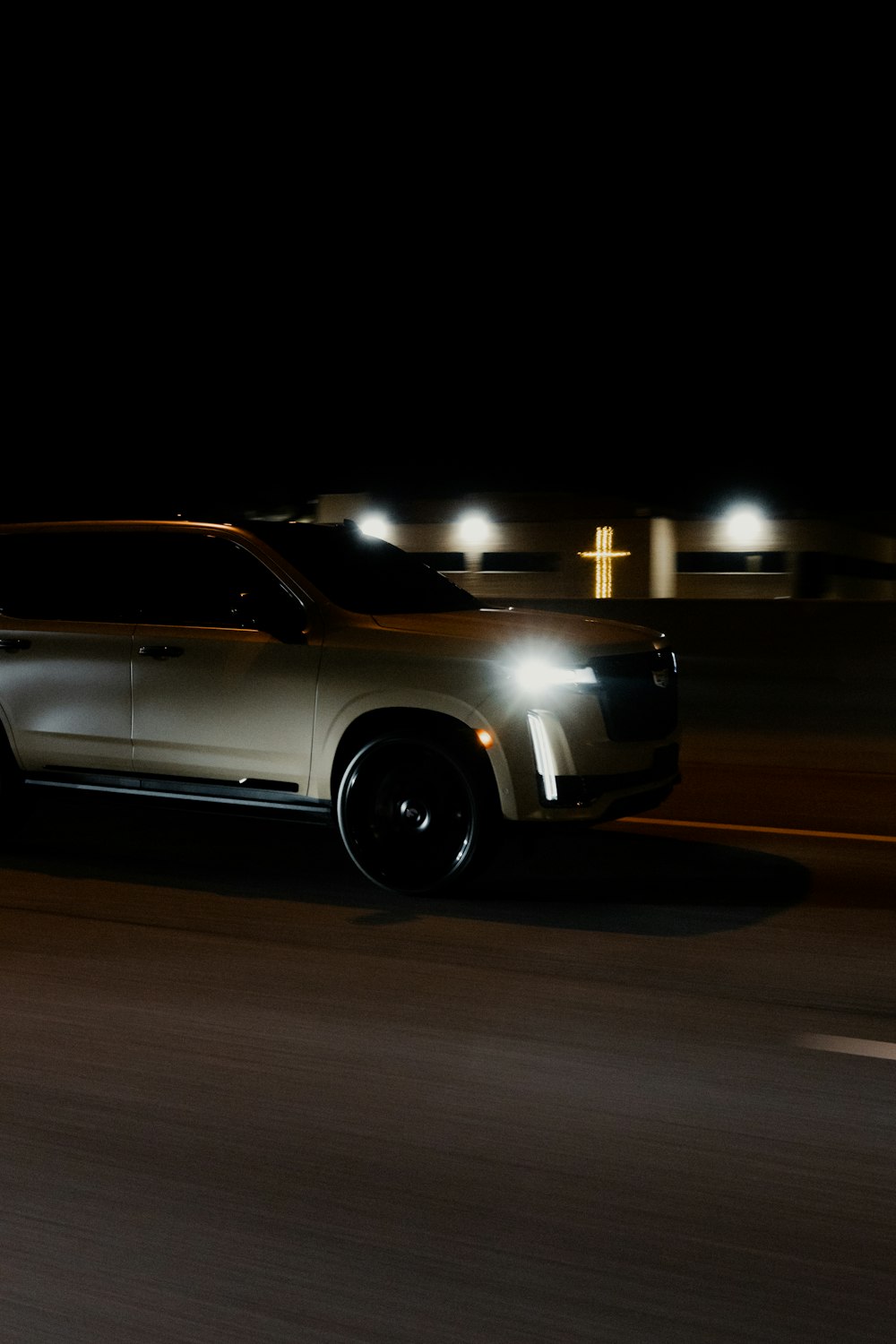 a silver suv driving down a street at night