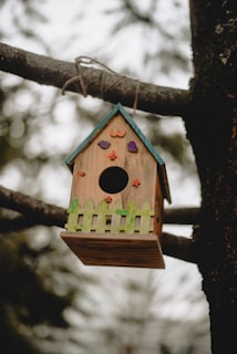 Handcrafted wooden bird feeder shaped like a small cottage with intricate carvings.
