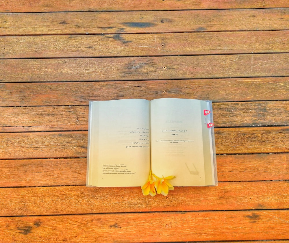 Un libro abierto sobre una mesa de madera con una flor