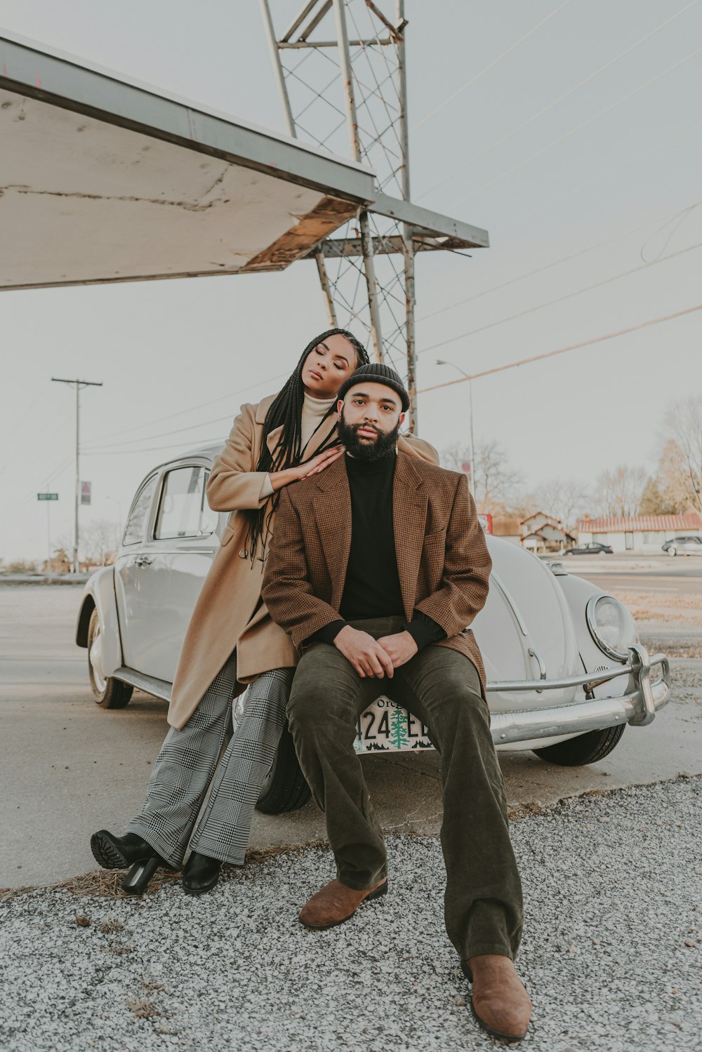 um homem e uma mulher sentados em um carro em frente a um posto de gasolina