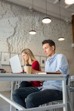 Young people studying together at a cafe table with laptops and notebooks.