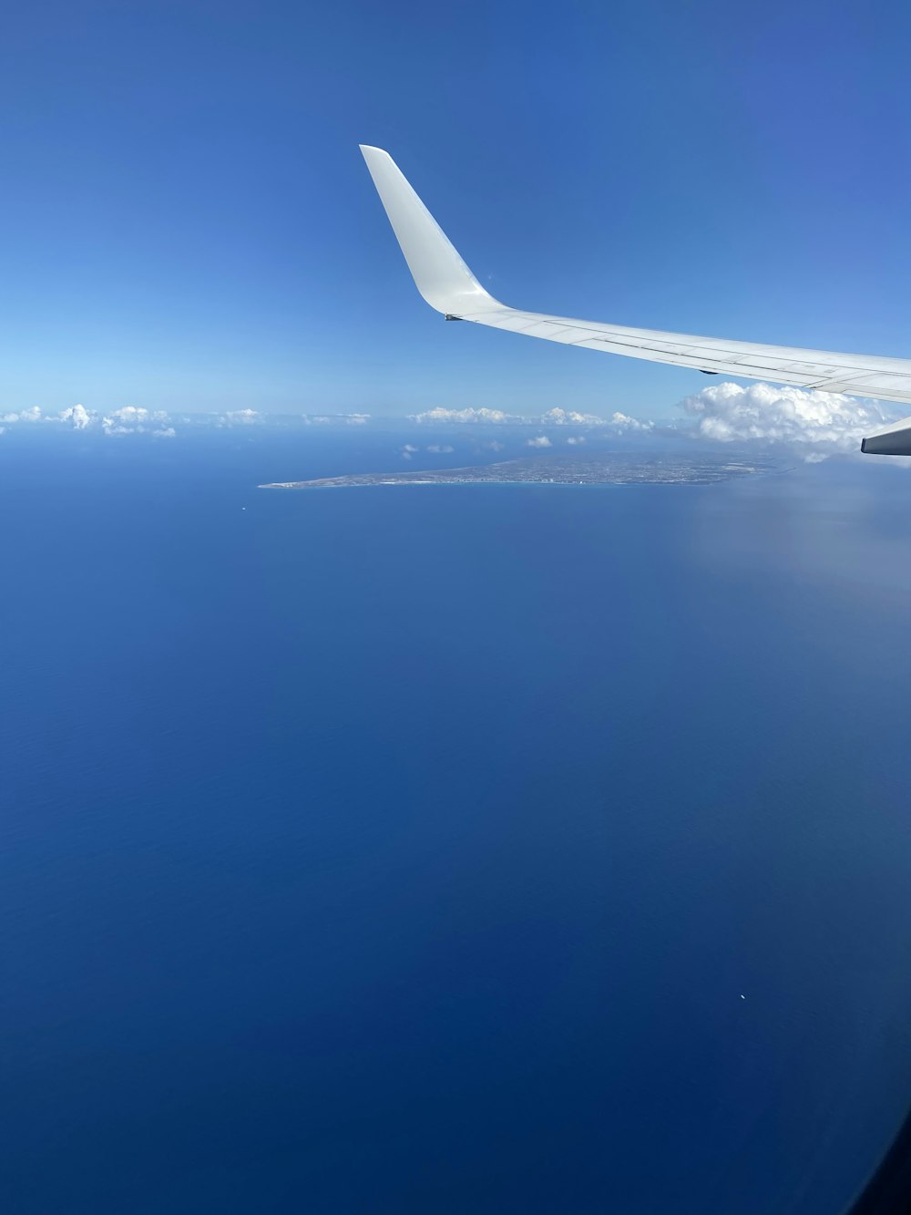 the wing of an airplane flying over the ocean