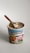 Ben & Jerry's ice cream tub labeled 'Netflix & Chilll'd Non-Dairy' is topped with light-colored ice cream. A wooden spoon is sticking out of the ice cream, suggesting it's ready to be eaten. The label shows a pretzel and a swirl of peanut butter, hinting at the flavors.