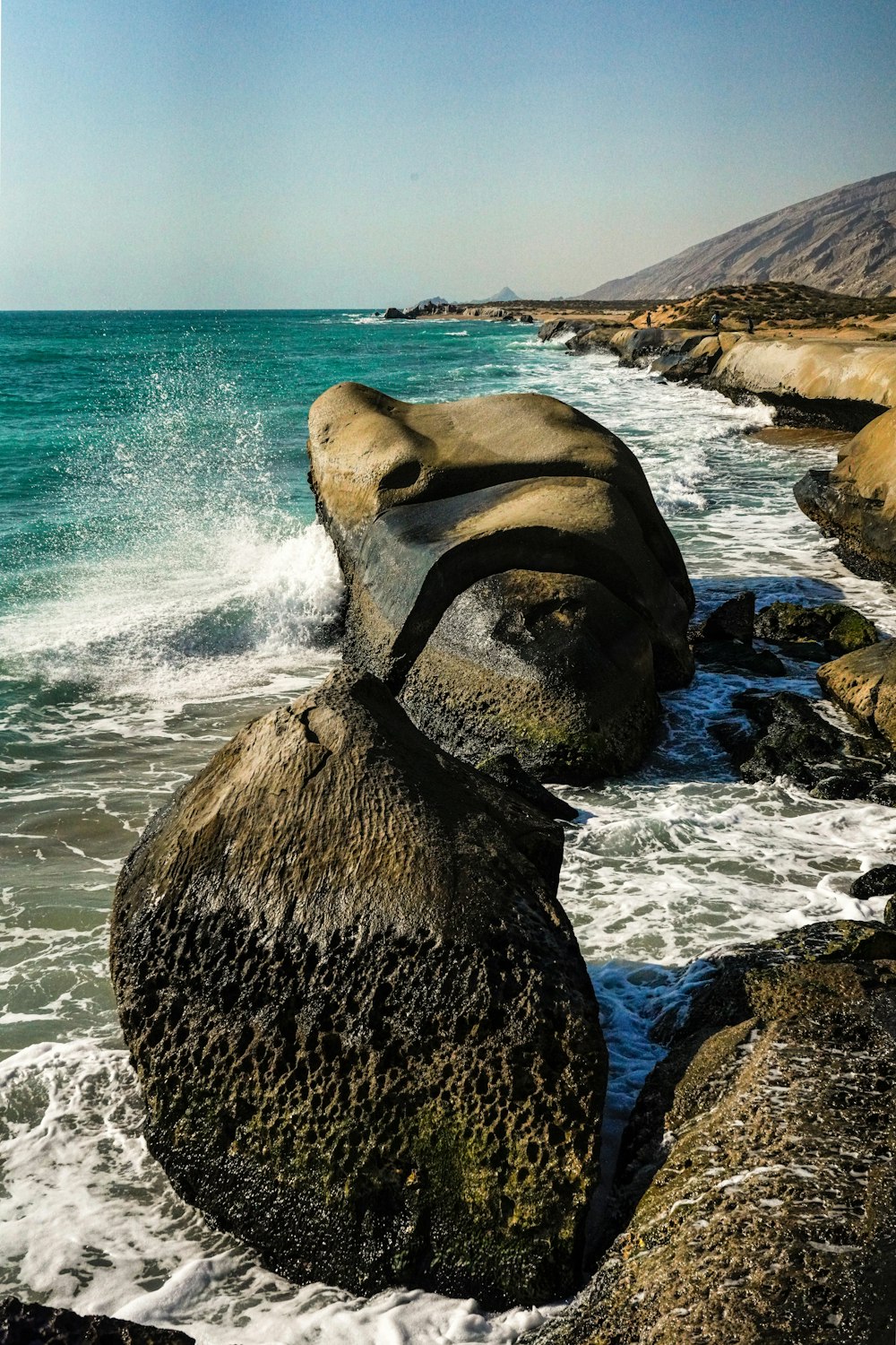 a large rock sitting on top of a beach next to the ocean