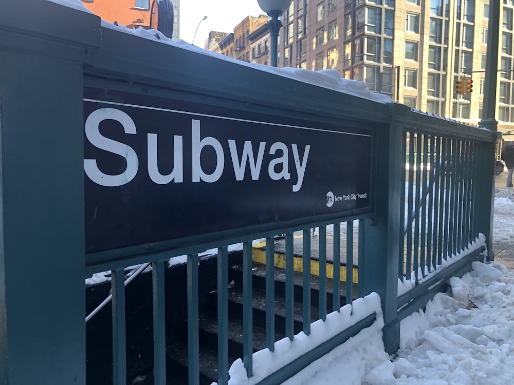 a subway sign on a fence in the snow