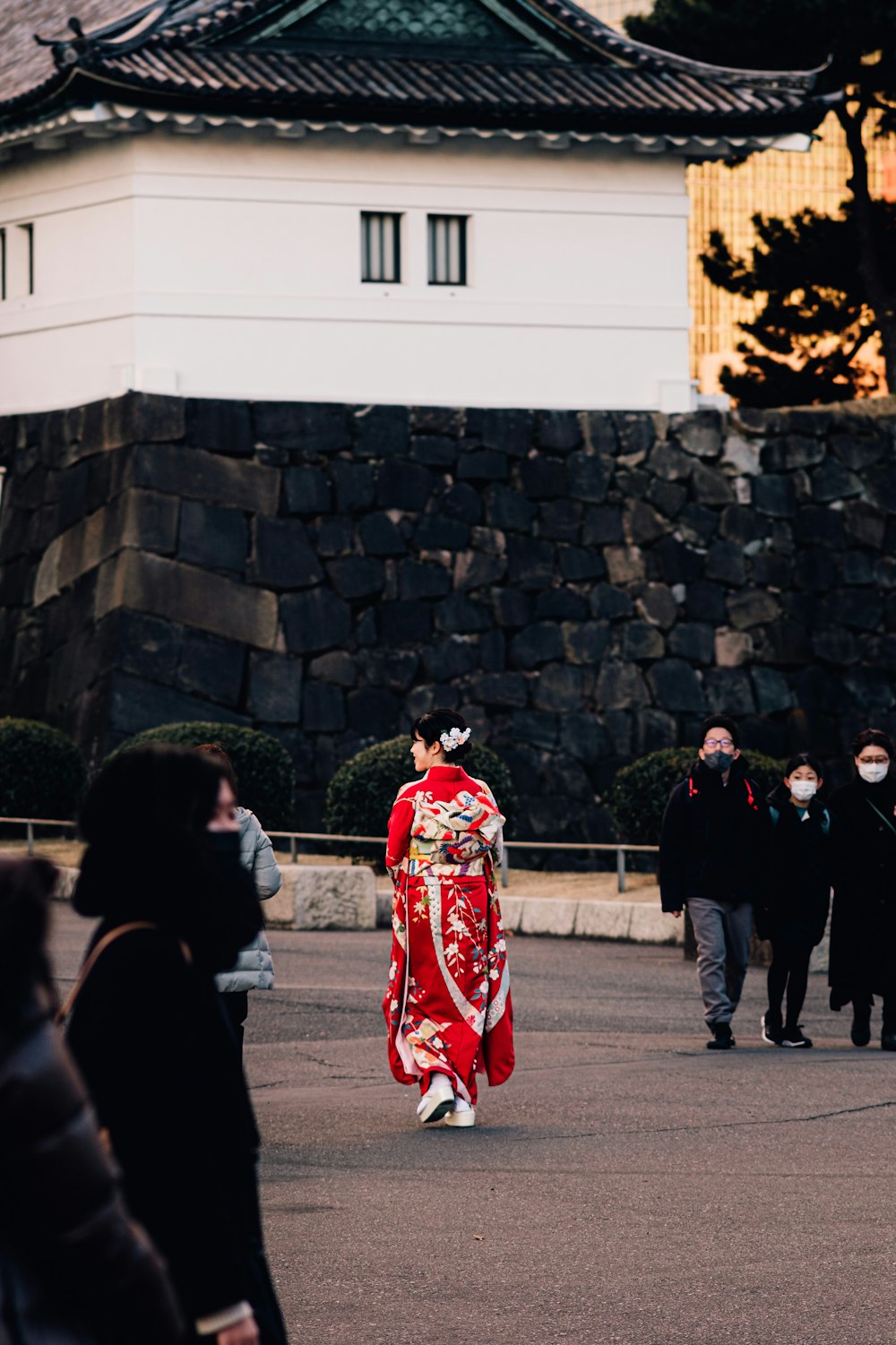 a woman in a red kimono walking down a street