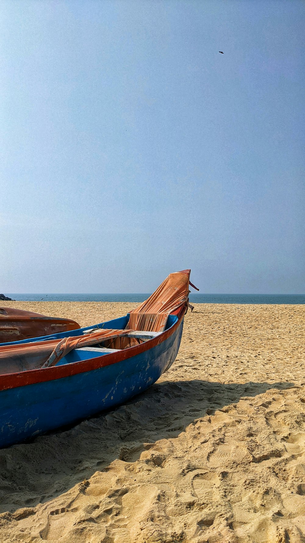 a blue boat sitting on top of a sandy beach