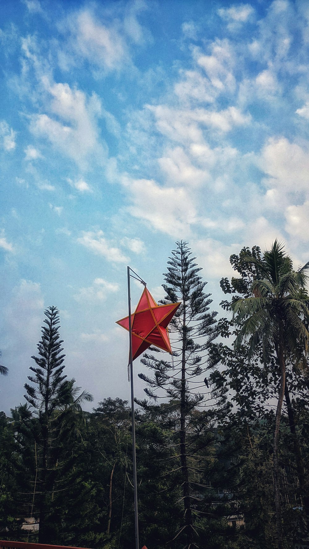 a large red star on a pole in front of some trees