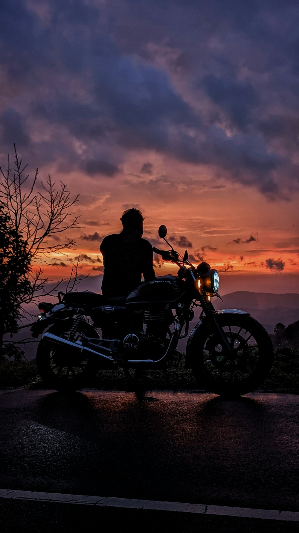 a person sitting on a motorcycle at sunset
