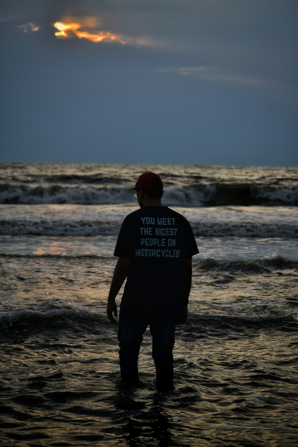 a man standing in the ocean at sunset