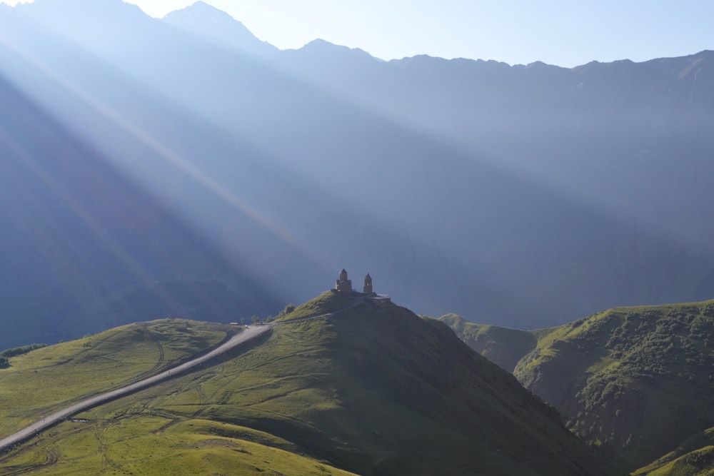 the sun shines on a grassy hill with a road running through it