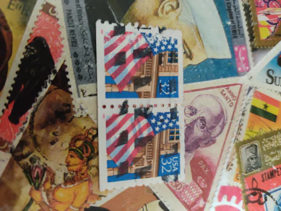 A person sending an email request on a laptop with a background of stamp collections.